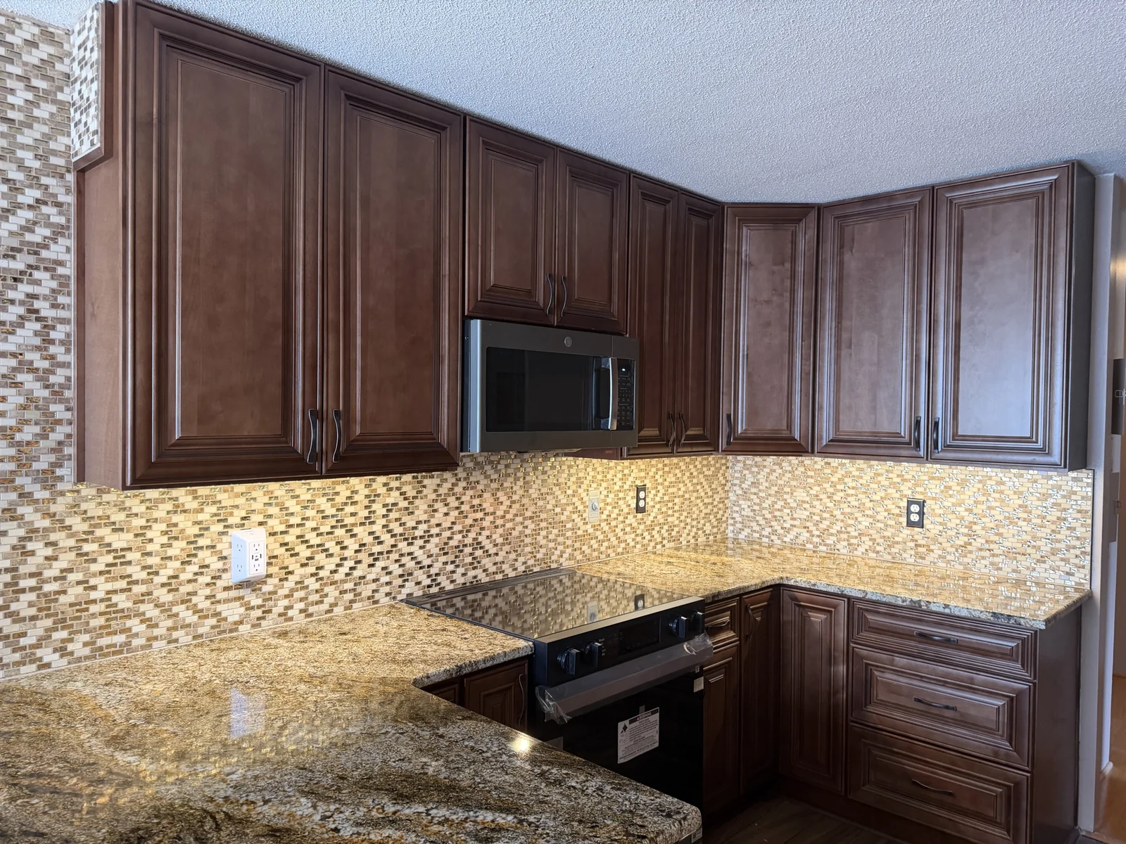 Gold and brown granite kitchen countertops with dark wood cabinets in Kansas City