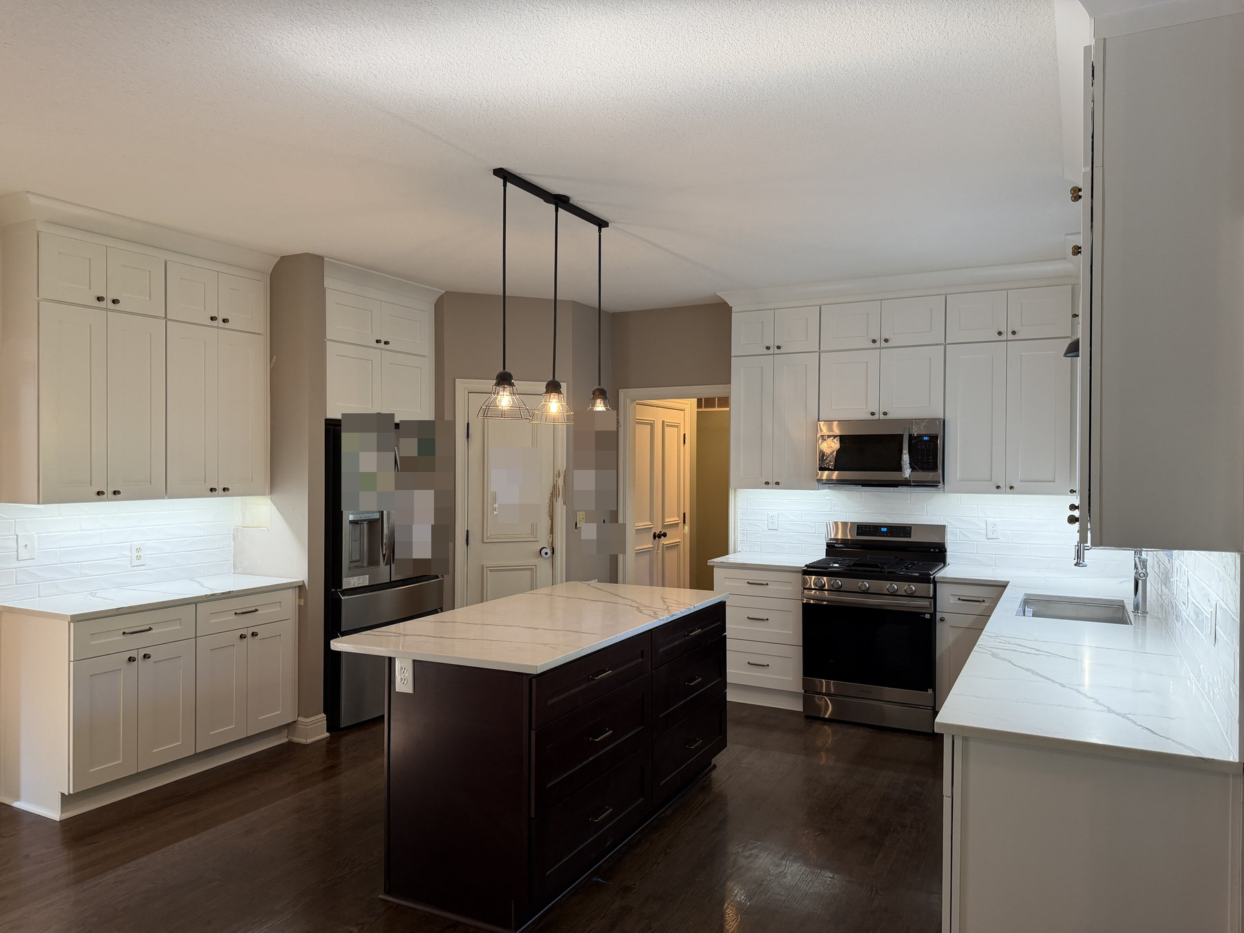 Ebony shaker island with drawer bases and white perimeter cabinets with stacked crown in a Leawood, KS kitchen
