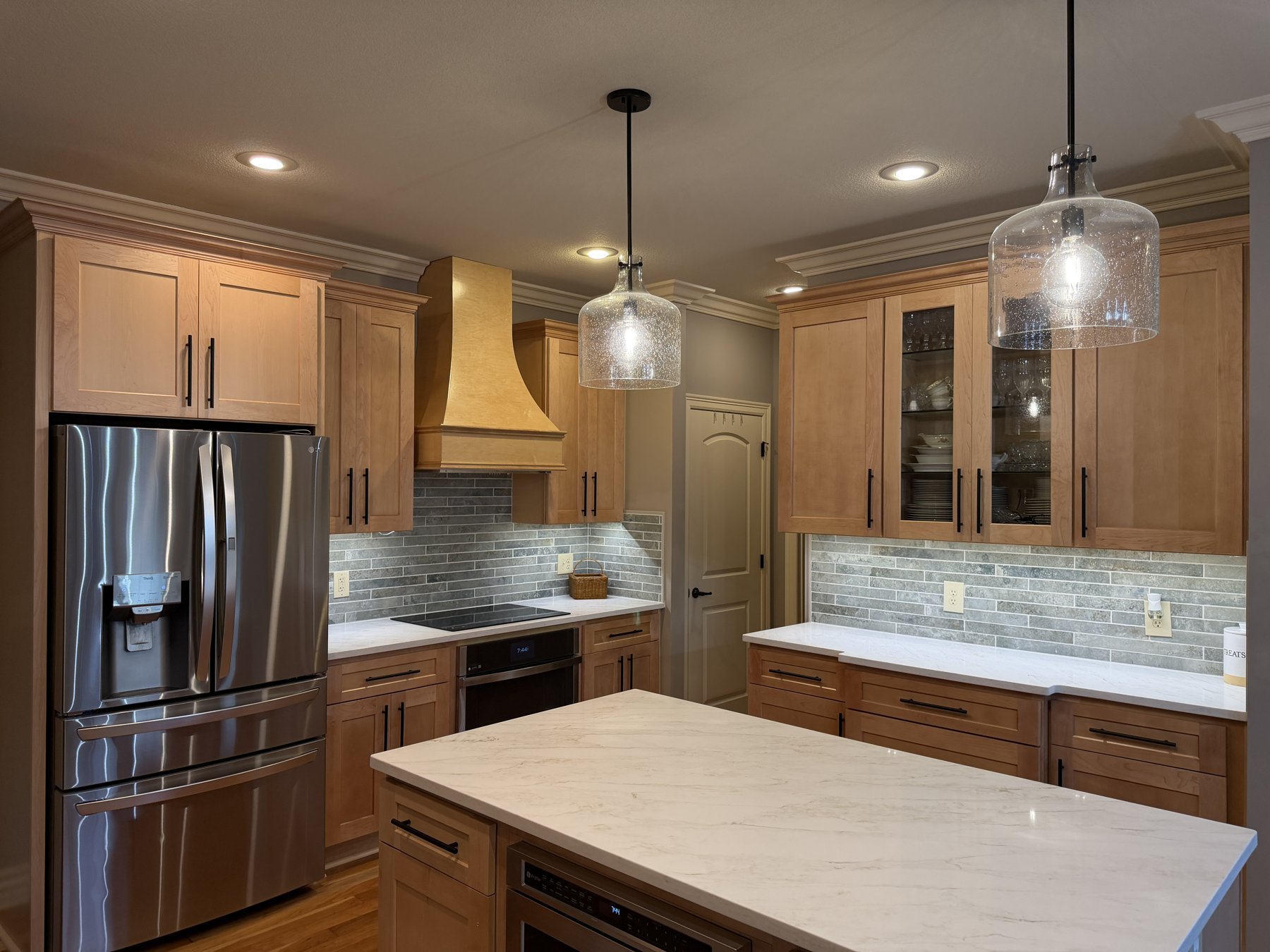 Sunny Maple shaker cabinets, custom hood and Calacatta quartz island in a Lee's Summit, MO kitchen remodel