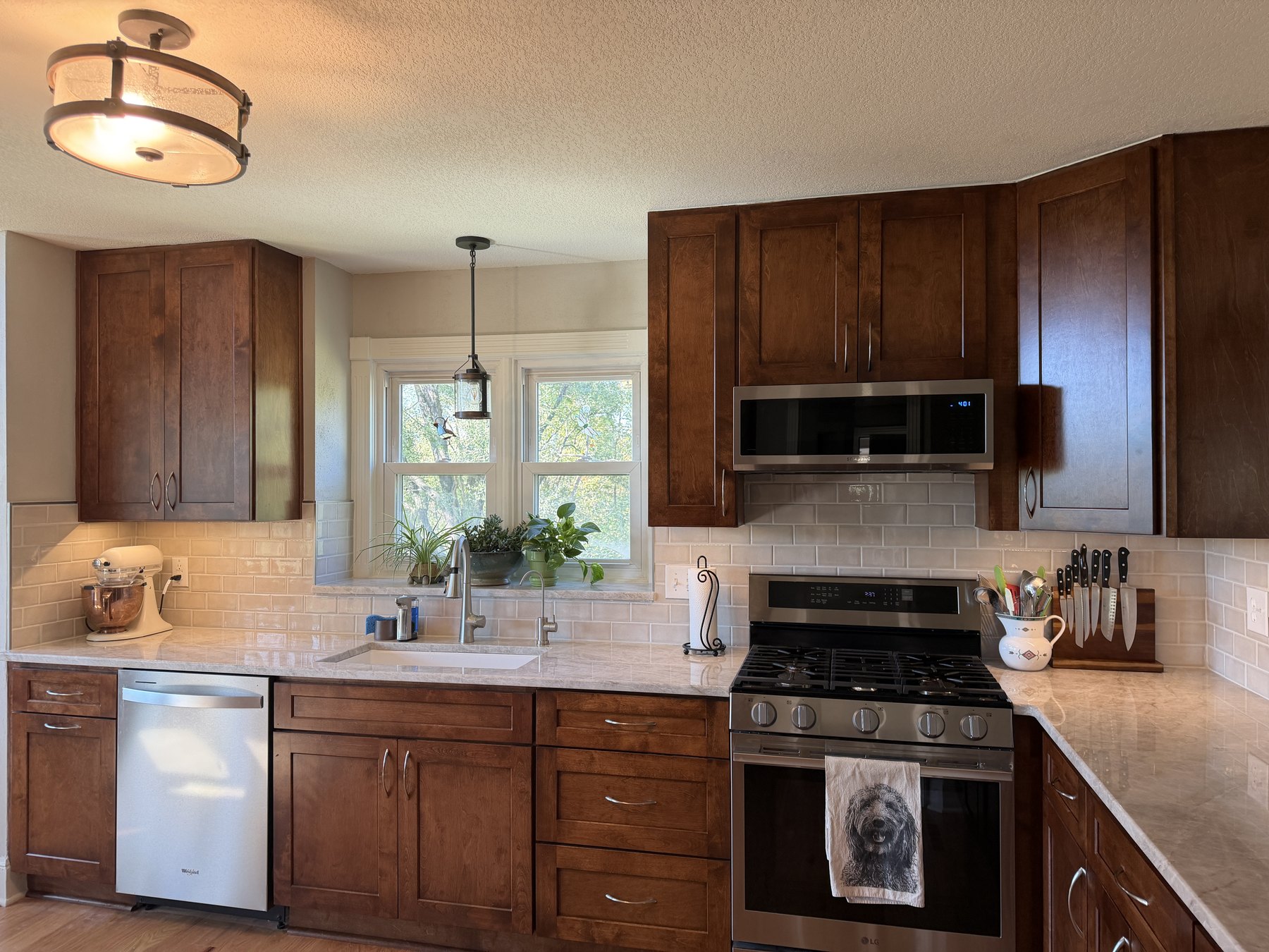 Stained shaker cabinets, Taj Mahal quartzite counter and tile backsplash with under-cabinet lighting in a Liberty, MO kitchen