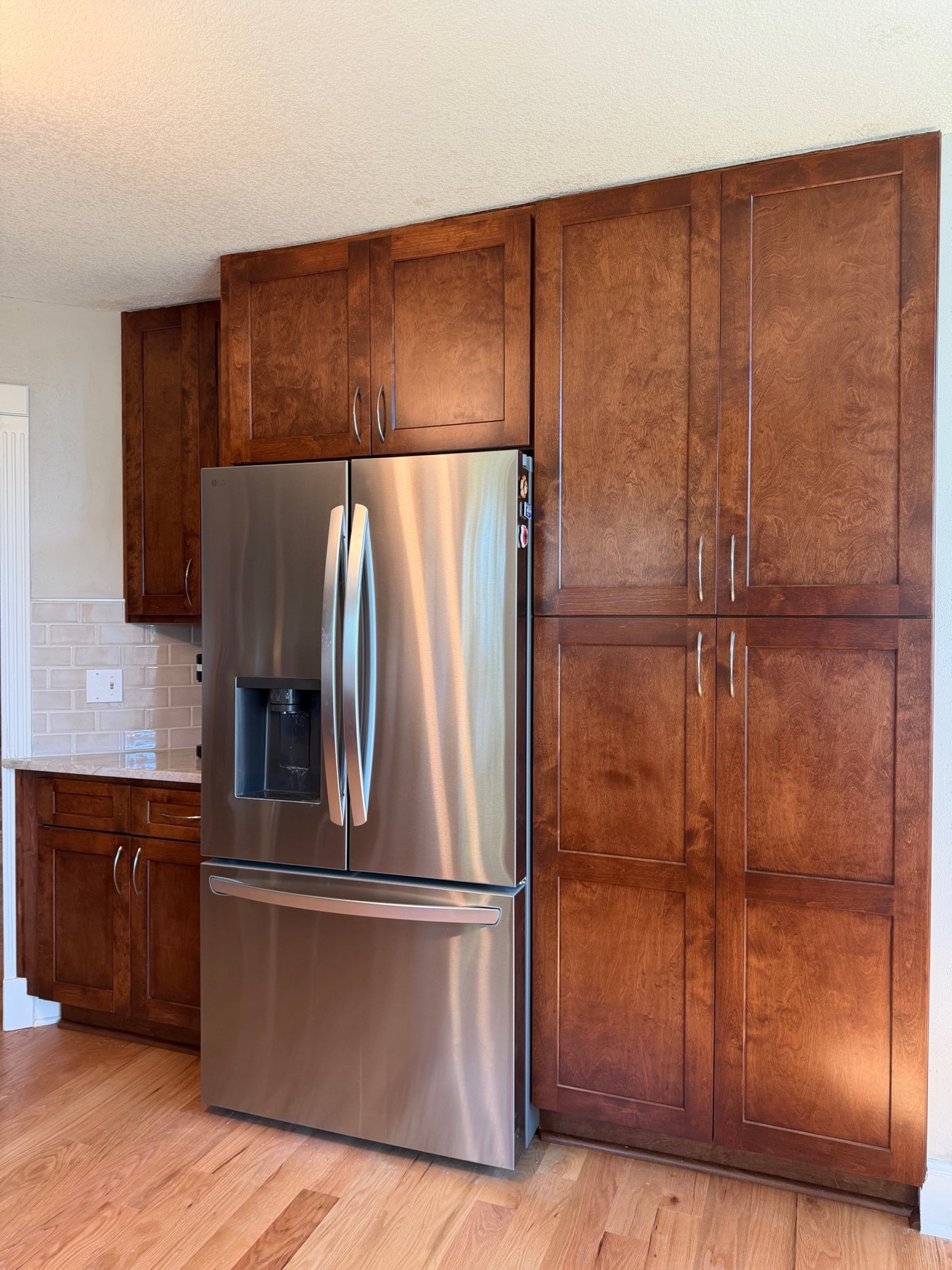 Tall stained shaker pantry cabinets beside the refrigerator in a Liberty, MO kitchen remodel