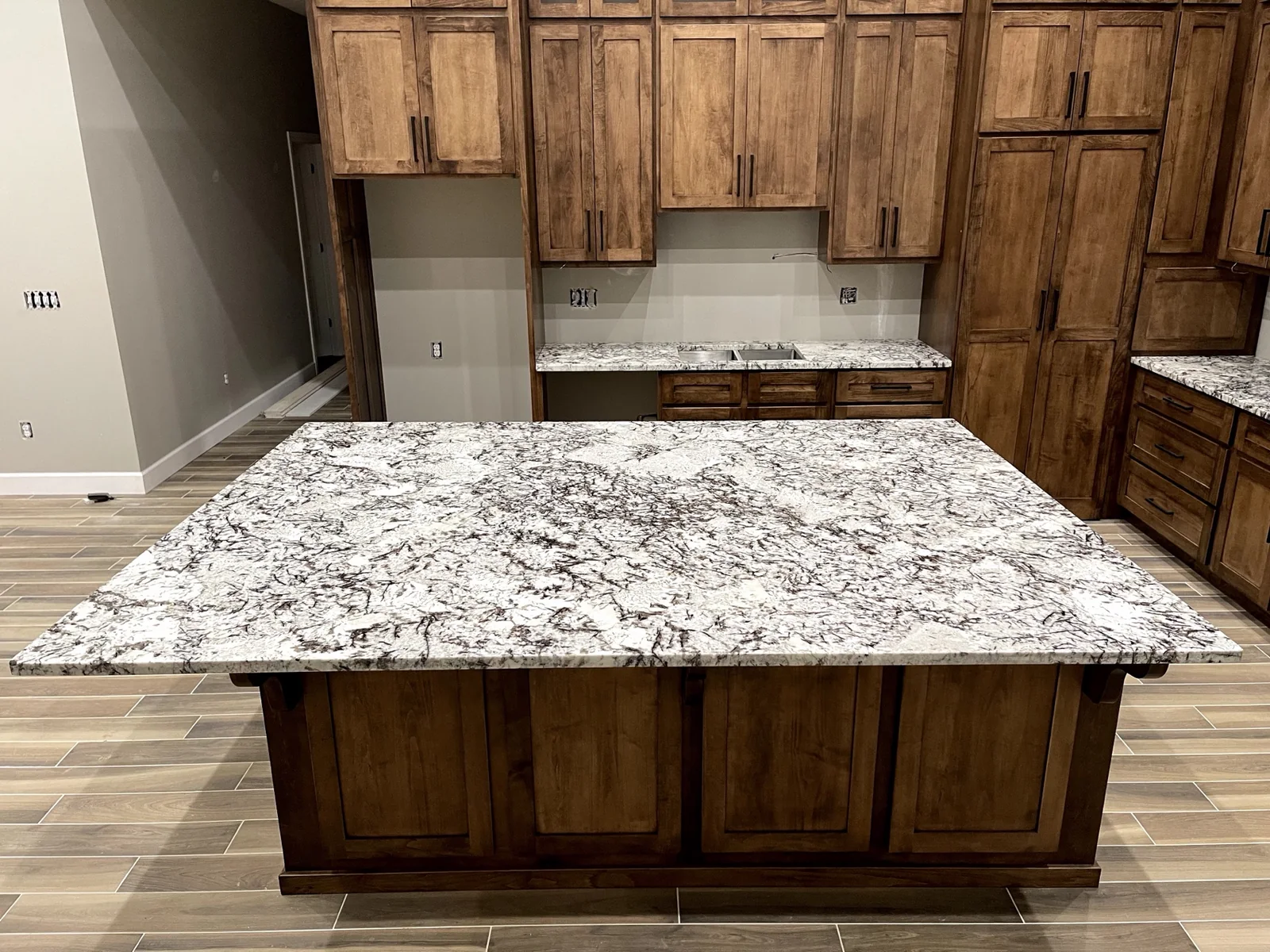 White and gray granite island with wood cabinets installed by KC Cabinetry & Stone in Kansas City