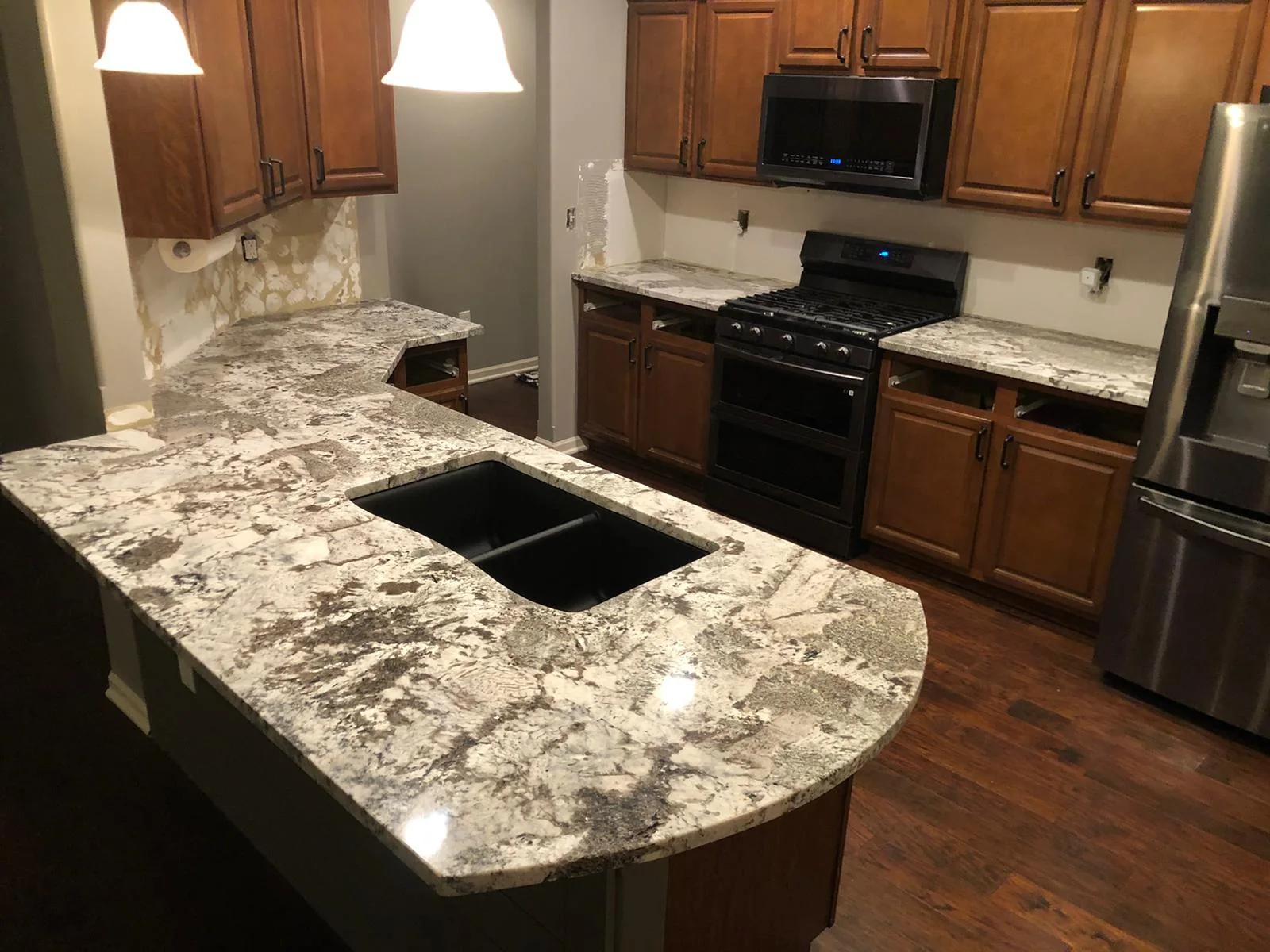 White and gray granite peninsula countertops with double-bowl sink in a Kansas City kitchen